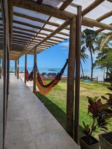 a hammock hanging from a pergola next to a beach at Slater's House - Casa de praia em frente ao mar in Santa Luzia