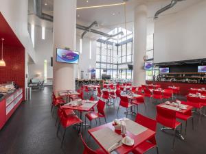 una sala da pranzo con sedie rosse e tavoli in un ristorante di Ramada Encore by Wyndham Puebla a Puebla