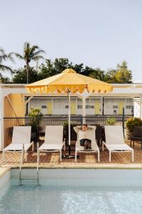 a dog laying in a chair under an umbrella next to a pool at Port Broughton Hotel and Sunnyside Motel in Port Broughton