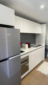 La cuisine est équipée de placards blancs et d'un réfrigérateur en acier inoxydable. dans l'établissement F1 standing vue mer Anse Vata, à Nouméa