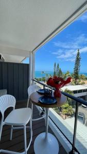 a balcony with a table and chairs and a view of the ocean at F1 standing vue mer Anse Vata in Noumea