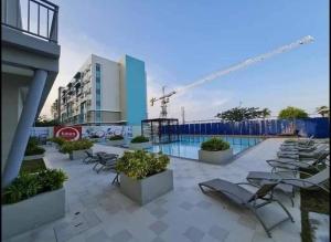 a hotel patio with lounge chairs and a pool at Warm Time Cabin 2BR Condo Unit in Dumaguete