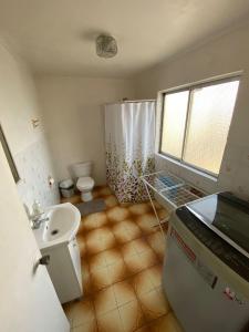 La salle de bains est pourvue d'un lavabo, de toilettes et d'une douche. dans l'établissement Central y Tranquilo alojamiento, à Villa Alemana