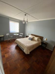 1 dormitorio con cama, mesa y ventana en Central y Tranquilo alojamiento, en Villa Alemana