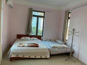 a bedroom with two beds and two windows at Quanho Villa in Bắc Ninh