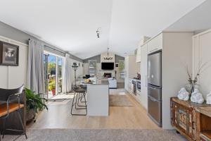 an open kitchen and living room with white appliances at Hunter Lodge - Papamoa Beach Holiday Home in Papamoa