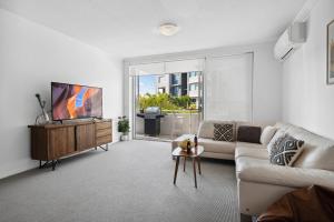 a living room with a couch and a tv at Luxury Stays Varsity-Robina-Bond in Gold Coast