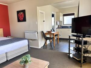 納爾遜的住宿－阿卡迪亞汽車旅館，一间卧室配有一张床和一张桌子及一台电视