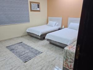 a bedroom with two beds and a table and a window at Ayser 1 in Al Madinah