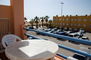 un balcón con una mesa y un aparcamiento con coches en Apartamento Los Lances II, en Tarifa