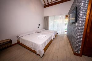 1 dormitorio con cama y pared de ladrillo en Las Hamacas Hotel, en Sauce