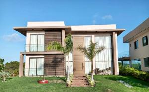 a house with palm trees in front of it at Casa da Laguna - Costa do Sauipe in Costa do Sauipe