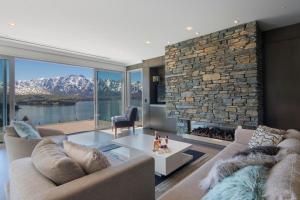 a living room with two couches and a stone fireplace at The Views and Spa by Staysouth in Queenstown