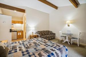 ein Schlafzimmer mit einem Bett, einem Tisch und einem Sofa in der Unterkunft Cedarbrook Deluxe Two Bedroom Suite with outdoor heated pool 20910 in Killington