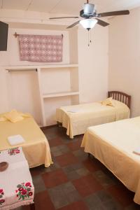een kamer met 2 bedden en een plafondventilator bij Hotel Hellenika in León
