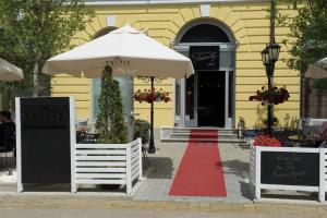 a yellow building with a white umbrella and a red carpet at Bed & Breakfast Twenty in Kikinda