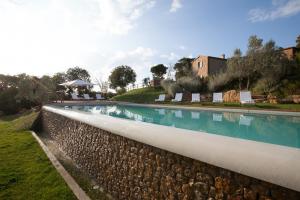 a large swimming pool with a stone retaining wall at Borgo Sant'Ambrogio - Resort in Pienza