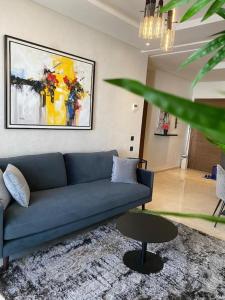 ein Wohnzimmer mit einem blauen Sofa und einem Gemälde in der Unterkunft Appartement de luxe ,piscine,parking,Terrasse in Agadir
