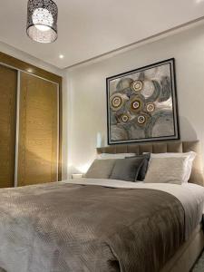 ein Schlafzimmer mit einem großen Bett und einem Gemälde an der Wand in der Unterkunft Appartement de luxe ,piscine,parking,Terrasse in Agadir