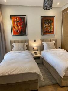 2 Betten in einem Schlafzimmer mit Gemälden an der Wand in der Unterkunft Appartement de luxe ,piscine,parking,Terrasse in Agadir