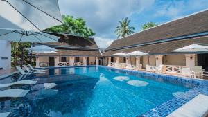 a swimming pool with white chairs and umbrellas at JingLand Hotel Luangprabang in Luang Prabang