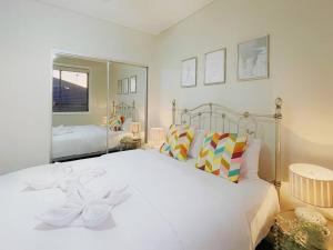 1 dormitorio con 1 cama blanca grande con almohadas en KozyGuru The Ponds Nearly New Cheerful Holiday House with Extra Entertainment Space NTP017, en Riverstone