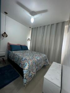 ein Schlafzimmer mit einem Bett mit blauen Kissen in der Unterkunft Biquinha - Praça 22 de Janeiro in São Vicente