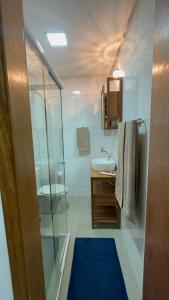 une salle de bain avec une douche en verre et un lavabo dans l'établissement Biquinha - Praça 22 de Janeiro, à São Vicente