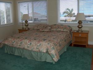 a bedroom with a bed with two night stands and two windows at Moana Hale Nui in Hauula
