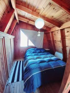 1 dormitorio con 1 cama en una cabaña de madera en El Canto de la Ballena en Puerto Pirámides