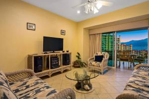 a living room with couches and a television and a balcony at Beach Front-Ocean Views-Marina Luxury Condo-BVG in Puerto Vallarta