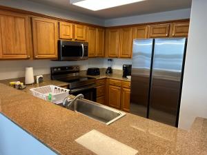 a kitchen with wooden cabinets and a stainless steel refrigerator at Big Pool, stunning Lakeview, Sunrise, Disney # 710 in Orlando