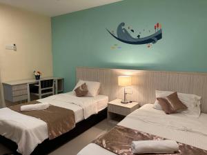 a bedroom with two beds and a surfboard on the wall at Laguna Raudhah Apartment in Lumut