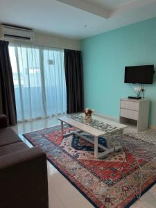 a living room with a coffee table and a television at Laguna Raudhah Apartment in Lumut