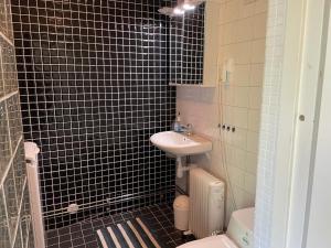 a black tiled bathroom with a sink and a toilet at Holiday home SURAHAMMAR in Surahammar