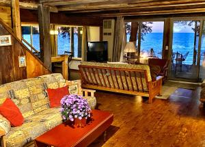 een woonkamer met een bank en uitzicht op de oceaan bij Pine Cottage On Secret Cove in Sodus