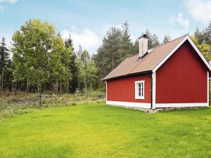 a red and white barn in a grassy field at Holiday home Björklinge in Björklinge
