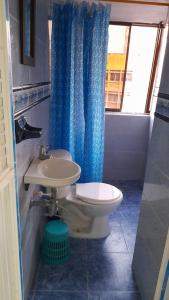 a bathroom with a toilet and a blue shower curtain at EDIFICIO MENDEZ in Cartagena de Indias