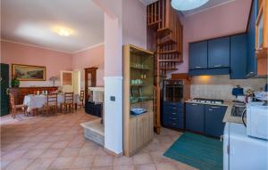 a kitchen with blue cabinets and a dining room at Cozy Apartment In Miglianico With Wifi in Miglianico