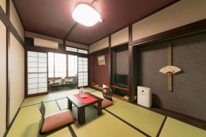a room with a table and chairs and a television at Ryokan Asunaro in Takayama