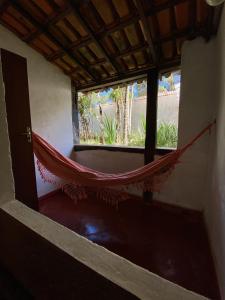 a hammock in a room with a window at Pousada Kokopelli in Lavras Novas