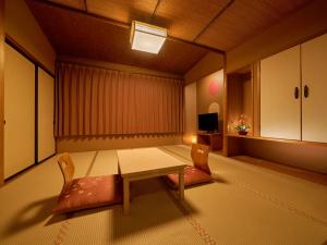 a room with a table and chairs and a television at Yukai Resort Hana-Saichoraku in Kaga