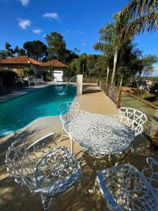 uma mesa e cadeiras ao lado de uma piscina em Pousada Kokopelli em Lavras Novas