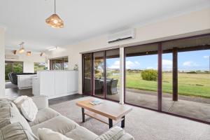 a living room with a couch and a table at Sea Breeze - Spacious home with lovely ocean views in Port Elliot