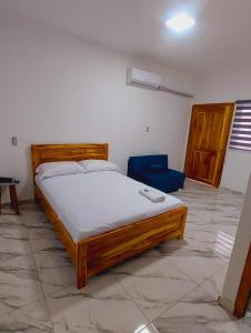 a bedroom with a wooden bed and a blue chair at Hostal Amelia de la Rosa in Manta