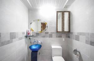 uma casa de banho com um WC azul e um espelho. em Doyosae Hanok Pension em Suncheon