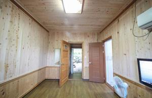 スンチョンにあるDoyosae Hanok Pensionの木製の壁とドア、テレビが備わる客室です。
