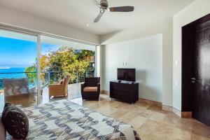 a bedroom with a bed and a tv and a balcony at Amapas ocean view condo in Puerto Vallarta