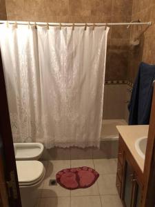 ein Badezimmer mit einem weißen Duschvorhang und einem WC in der Unterkunft Casa familiar Nivel Superior in San Fernando del Valle de Catamarca