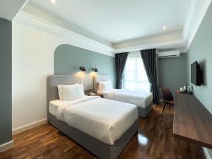 a hotel room with two beds and a television at Hotel Seri Costa in Melaka